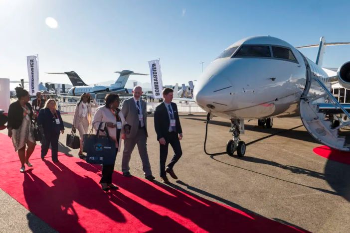 VIPS walk past a business jet at an air show