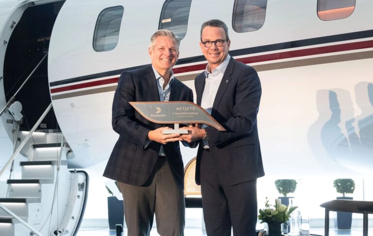 Two men at a podium during a business jet first-delivery ceremony