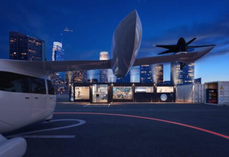 Rendering of a Skyports-branded vertiport at night with an aircraft on the landing pad and another in flight above a city skyline